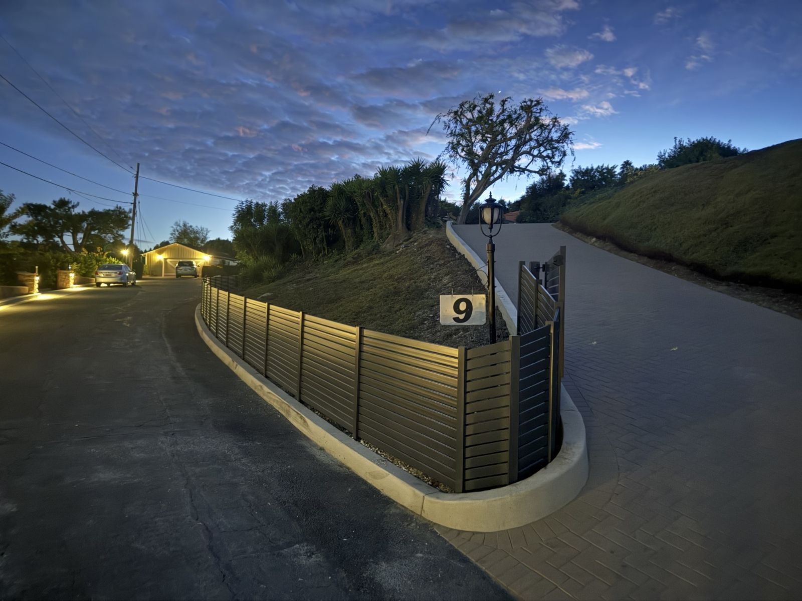 horizontal aluminum fence curving driveway at night